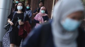 Sejumlah karyawan menggunakan masker saat keluar dari kantor Bank BRI, Jakarta, Kamis (23/1). [Suara.com.Angga Budhiyanto]