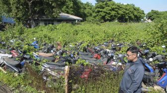 Warga melintasi kendaraan bermotor yang terparkir daerah Teluk Pucung di Bekasi, Jawa Barat, Kamis (23/1). [ANTARA FOTO/Fakhri Hermansyah]