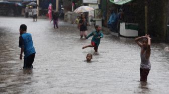 Sejumlah anak bermain di jalan yang terendam banjir di kawasan Duren Tiga, Jakarta Selatan, Jumat (24/1). [Suara.com/Angga Budhiyanto]