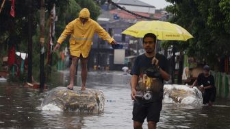 Sejumlah warga melintasi jalan yang terendam banjir di kawasan Duren Tiga, Jakarta Selatan, Jumat (24/1). [Suara.com/Angga Budhiyanto]