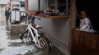 Seorang anak beraktivitas di rumahnya yang terendam banjir di kawasan Duren Tiga, Jakarta Selatan, Jumat (24/1). [Suara.com/Angga Budhiyanto]