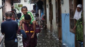 Sejumlah warga melintasi jalan yang terendam banjir di kawasan Duren Tiga, Jakarta Selatan, Jumat (24/1). [Suara.com/Angga Budhiyanto]