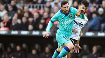 Bek Valencia Ezequiel Garay (kanan) menantang pemain depan Lionel Messi (kiri) selama pertandingan sepak bola liga Spanyol Valencia melawan Barcelona di Stadion Mestalla, Valencia, Spanyol, Sabtu (26/1).[JOSE JORDAN / AFP]