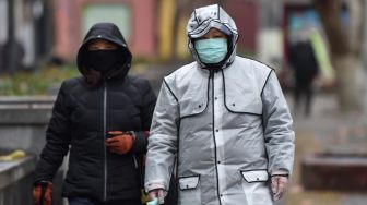 Staf medis yang mengenakan pakaian untuk melindungi dari virus yang sebelumnya tidak dikenal berjalan di luar rumah sakit di Wuhan, Cina, Minggu (26/1). [Hector RETAMAL / AFP]
