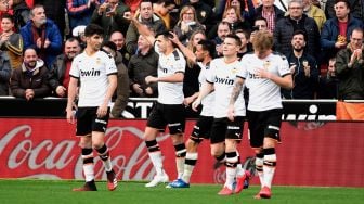 Para pemain Valencia merayakan setelah pemain belakang Spanyol Jordi Alba mencetak gol bunuh diri selama pertandingan sepak bola liga Spanyol Valencia melawan Barcelona di Stadion Mestalla, Valencia, Spanyol, Sabtu (26/1). [JOSE JORDAN / AFP]