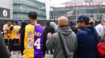 Penggemar Kobe Bryant berduka saat berkumpul di depan Staples Center, Los Angeles Lakers, Amerika, Minggu (26/1). [Frederic J. Brown / AFP]