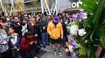 Penggemar Kobe Bryant berduka saat berkumpul di depan Staples Center, Los Angeles Lakers, Amerika, Minggu (26/1). [Frederic J. Brown / AFP]