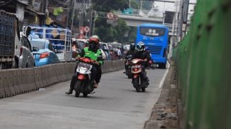 Pengendara sepeda motor berusaha menghindari razia Polisi lalu lintas di jalur khusus Transjakarta Sultan Agung, Manggarai, Jakarta, Jumat (31/1).  [Suara.com/Angga Budhiyanto]