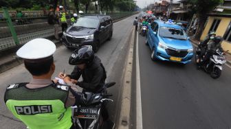 Petugas Kepolisian menilang pengendara motor yang memasuki jalur khusus Transjakarta Sultan Agung, Manggarai, Jakarta, Jumat (31/1). [Suara.com/Angga Budhiyanto]