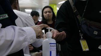 Penumpang yang mencuci tangan dengan cairan astiseptik di Stasiun Gambir, Jakarta Pusat, Jumat (31/01). [Suara.com/Alfian Winanto]
