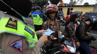 Petugas Kepolisian menilang pengendara motor yang memasuki jalur khusus Transjakarta Sultan Agung, Manggarai, Jakarta, Jumat (31/1). [Suara.com/Angga Budhiyanto]