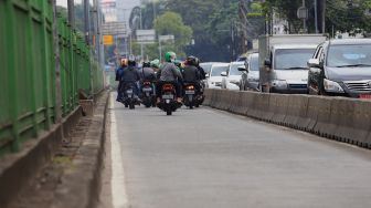 Pengendara sepeda motor berusaha menghindari razia Polisi lalu lintas di jalur khusus Transjakarta Sultan Agung, Manggarai, Jakarta, Jumat (31/1).  [Suara.com/Angga Budhiyanto]