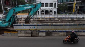 Seorang pengendara motor melintas di samping proyek pembangunan underpass Senen Extension di Pasar Senen, Jakarta, Senin (3/2). [Suara.com/Angga Budhiyanto]