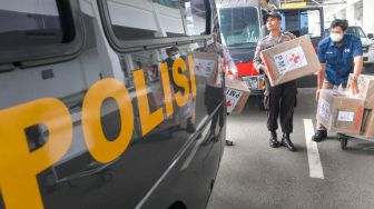 Personel Polisi mengangkat kardus yang berisi masker bantuan dari PMI pusat yang baru tiba di Bandara Raden Sadjad, Ranai, Natuna, Kepulauan Riau, Selasa (4/2).  [ANTARA FOTO/M Risyal Hidayat]