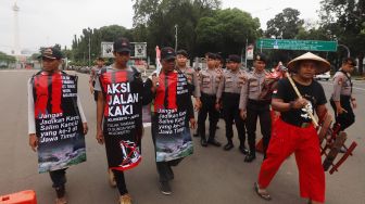 Tiga warga asal Mojokerto didampingi seorang aktivis berjalan menuju Istana Kepresidenan, Jakarta, Kamis (6/2). [Suara.com/Angga Budhiyanto]