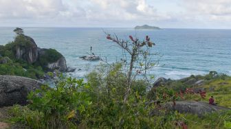 Seorang wisatawan duduk di atas gugusan batu granit di Geopark Tanjung Senubing, Ranai, Natuna, Kepulauan Riau, Minggu (9/2). [ANTARA FOTO/M Risyal Hidayat]