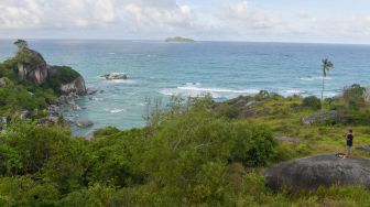 Seorang wisatawan berdiri di atas gugusan batu granit di Geopark Tanjung Senubing, Ranai, Natuna, Kepulauan Riau, Minggu (9/2). [ANTARA FOTO/M Risyal Hidayat]