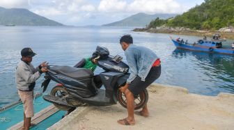 Penumpang berusaha menurunkan sepeda motornya dari kapal motor setibanya di Dermaga Pelabuhan Selat Lampa, Natuna, Kepulauan Riau, Sabtu (8/2). [ANTARA FOTO/M Risyal Hidayat]