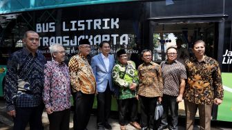 Wakil Ketua DPR Koordinator Bidang Politik, Hukum dan Keamanan, Azis Syamsuddin (kiri) dan Ketua Umum Lembaga Dakwah Islam Indonesia (LDII), Abdullah Syam (kanan) berfoto bareng anggota LDII usai mencoba Bus listrik yang digagas LDII, Rabu (12/02). [Suara.com/Oke Atmaja]
