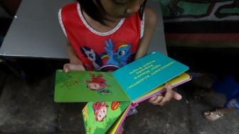 Seorang anak membaca di Taman Bacaan di kawasan Jembatan Lima, Jakarta,  Kamis (13/2). [Suara.com/Angga Budhiyanto]