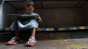 Seorang anak membaca di Taman Bacaan di kawasan Jembatan Lima, Jakarta,  Kamis (13/2). [Suara.com/Angga Budhiyanto]