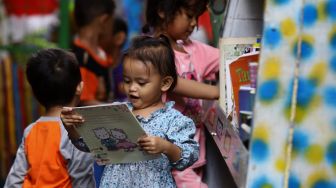 Seorang anak memilih buku di Taman Bacaan di kawasan Jembatan Lima, Jakarta,  Kamis (13/2). [Suara.com/Angga Budhiyanto]