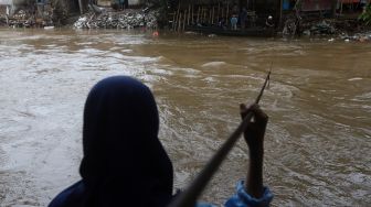 Seorang warga menunggu perahu eretan untuk menyeberangi Kali Ciliwung di kawasan Manggarai, Jakarta, Jumat (14/2). [Suara.com/Angga Budhiyanto]