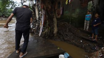 Seorang warga mengoperasikan perahu eretan untuk menyeberangi Kali Ciliwung di kawasan Manggarai, Jakarta, Jumat (14/2). [Suara.com/Angga Budhiyanto]