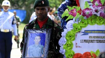 Prajurit TNI membawa foto dan peti jenazah korban kecelakaan Heli MI-17 saat upacara pelepasan di Hanggar Base Ops Lanud Silas Papare Sentani, Jayapura, Papua, Senin (17/2). [ANTARA FOTO/Gusti Tanati]
