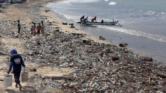 Nelayan dan warga beraktivitas di pantai yang dicemari sampah di Pantai Kedonganan, Badung, Bali, Jumat (21/2). [ANTARA FOTO/Nyoman Hendra Wibowo]