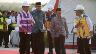 Presiden Joko Widodo (kiri) didampingi Plt Gubernur Aceh, Nova Iriansyah (kedua kiri) berjalan saat meninjau perkembangan pembangunan Seksi IV jalan tol di Desa Indra Puri, Kabupaten Aceh Besar, Aceh, Jumat ( 21/2). [ANTARA FOTO/Ampelsa]