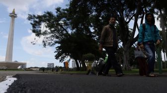 Sejumlah pengunjung melintas di atas aspal uji coba lintasan Formula E di kawasan Monumen Nasional (Monas), Jakarta, Sabtu (22/2). [Suara.com/Angga Budhiyanto]