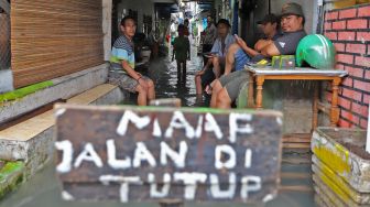 Aktivitas warga didepan rumahnya yang tergenang banjir di Petamburan II, Jakarta Pusat, Minggu (23/02). [Suara.com/Alfian Winanto]