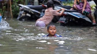 Seorang anak berenang saat banjir di Petamburan II, Jakarta Pusat, Minggu (23/02). [Suara.com/Alfian Winanto]
