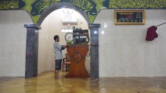 Warga meletakan alat pengeras suara ke atas mimbar di Masjid Jami' Al-Jamaah yang terendam banjir di Jalan Anyer, Menteng, Jakarta, Minggu (23/2).  [ANTARA FOTO/M Risyal Hidayat]
