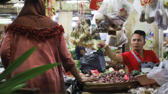 Pedagang memberikan kantong plastik yang berisi barang belanjaan pembeli  di Pasar Tradisional Pasar Minggu, Jakarta Selatan, Senin (24/02). [Suara.com/Alfian Winanto]

