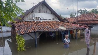 Seorang warga berada di depan rumahnya yang terendam banjir di Tirto, Pekalongan, Jawa Tengah, Senin (24/2). [ANTARA FOTO/Harviyan Perdana Putra]

