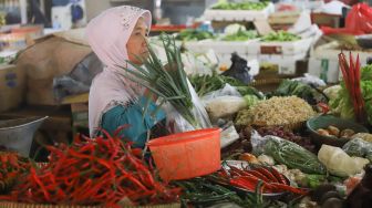 Pedagang membungkus sayuran jualannya kedalam kantong plastik di Pasar Tradisional Pasar Minggu, Jakarta Selatan, Senin (24/02). [Suara.com/Alfian Winanto]