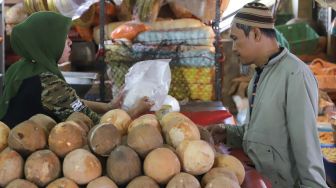 Pedagang membungkus parutan kelapa dengan kantong plastik di Pasar Tradisional Pasar Minggu, Jakarta Selatan, Senin (24/02). [Suara.com/Alfian Winanto]
