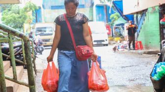 Pembeli sehabis berbelanja di Pasar Tradisional Pasar Minggu, Jakarta Selatan, Senin (24/02). [Suara.com/Alfian Winanto]