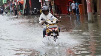 Seorang pengendara sepeda motor melintasi banjir yang merendam kawasan Pasar Baru, Jakarta Pusat, Selasa (25/2). [Suara.com/Angga Budhiyanto]
