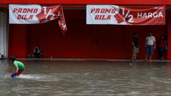 Seorang anak melintasi banjir yang merendam kawasan Pasar Baru, Jakarta Pusat, Selasa (25/2). [Suara.com/Angga Budhiyanto]