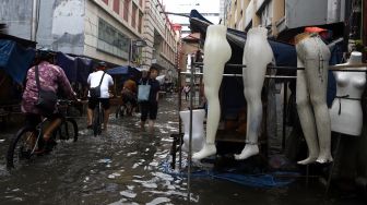 Pesepeda melintasi banjir yang merendam kawasan Pasar Baru, Jakarta Pusat, Selasa (25/2). [Suara.com/Angga Budhiyanto]