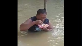 Kelewat Santuy! Pria Ini Makan di Tengah Banjir