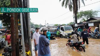 Kondisi Jalan Raya Pondok Gede yang tergenang banjir di Bekasi, Jawa Barat, Selasa (25/02). [Suara.com/Alfian Winanto]