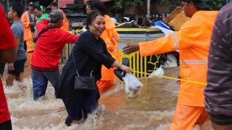 Warga menyebrangi banjir dengan bantuan tali di Jalan Raya Pondok Gede, Bekasi, Jawa Barat, Selasa (25/2).  [Suara.com/Alfian Winanto]