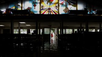 Seorang warga melihat Gereja Santo Kristoforus yang terendam banjir di kawasan Jalan Satria IV, Kelurahan Jelambar, Jakarta Barat, Selasa (25/2). [Suara.com/Angga Budhiyanto]  