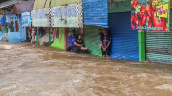 Aktivitas warga yang rumahnya tergenang banjir di Jalan Raya Pondok Gede, Bekasi, Jawa Barat, Selasa (25/02). [Suara.com/Alfian Winanto]
