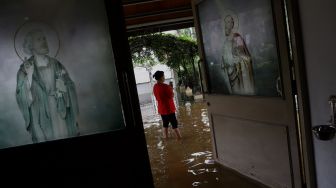 Seorang warga mengambil gambar Gereja Santo Kristoforus yang terendam banjir di kawasan Jalan Satria IV, Kelurahan Jelambar, Jakarta Barat, Selasa (25/2). [Suara.com/Angga Budhiyanto]  