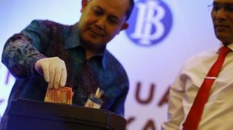 Direktur Departemen Pengelolaan Uang Yudi Haryamukti (kiri) memasukkan uang palsu ke dalam mesin pencacah uang saat Pemusnahan 50.000 Lembar Uang Rupiah Palsu di Gedung Sjafruddin Prawinegaran, Bank Indonesia, Jakarta, Rabu (26/2). [Suara.com/Angga Budhiyant